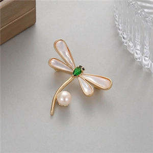 Détail macro de broche libellule avec ailes en nacre et pierre précieuse vert émeraude