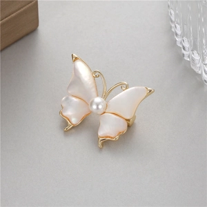 Détail de la broche papillon avec ailes en nacre et une perle blanche centrale sertie