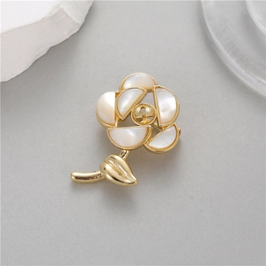 Détail d'une broche rose avec pétales en nacre blanche et tige en métal doré pour femme