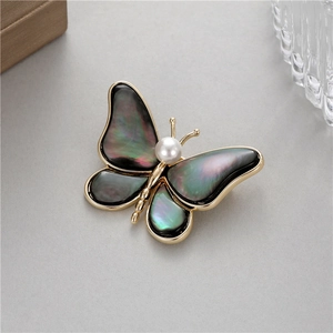 Élégante broche papillon avec ailes en nacre irisée et une perle blanche centrale fine