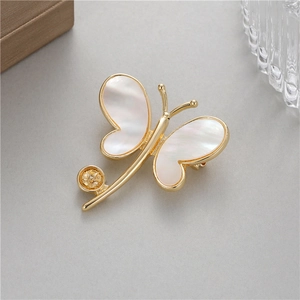 Détail d'élégante broche papillon avec ailes en nacre blanche et accents dorés