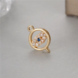 Macro detail of a 14K gold-plated Evil Eye charm with blue zircon and pavé stones