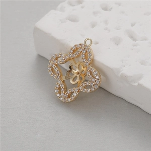 Golden flower pendant with white zircons on a textured stone display background