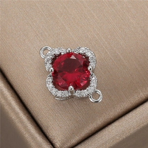 Macro shot of silver flower pendant with central red zircon and double ring connectors