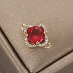 Detail of DIY four-leaf clover jewelry charm with red gemstone and gold plating
