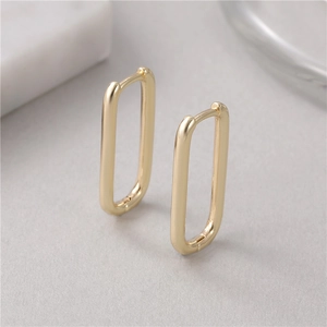 Close-up of thick rectangular gold hoop earrings with minimalist geometric design features