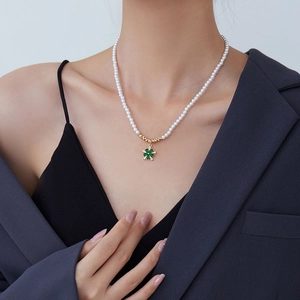 Elegant pearl choker necklace with a gold four-leaf clover pendant on a fashion model
