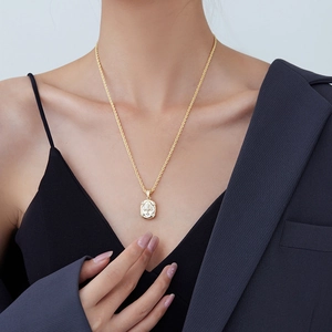 Golden necklace with a cross-shaped white zircon pendant worn over a black top