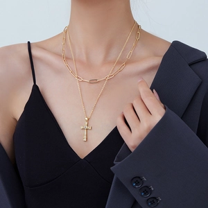 Double-layered gold-plated cross necklace with sparkling heart zircon on a female model