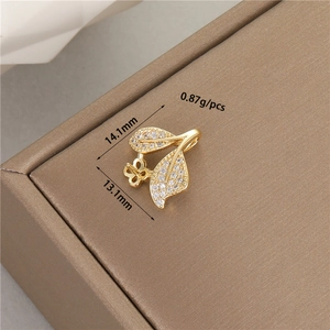 Macro shot of a 14K gold-plated leaf pendant with zircon inlay on leather texture
