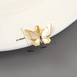 Macro shot of 14K gold bow charm with shell inlay and colorful gemstones detail