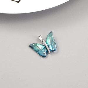 Macro view of blue butterfly pendant with 14K gold flakes and zircon inlay detail