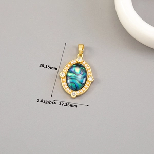 Macro detail of oval abalone shell pendant with pearl inlay and gold plated frame