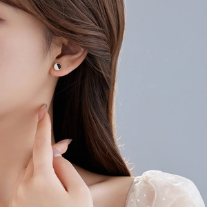 Boucles d'oreilles géométriques noir et blanc portées par un mannequin sur fond bleu