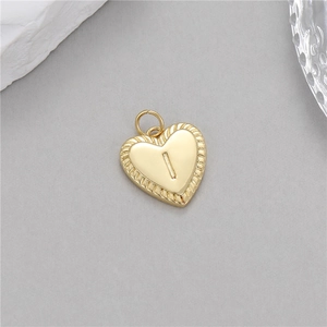 Vue macro du pendentif cœur doré avec lettre I en relief et texture à rayons solaires