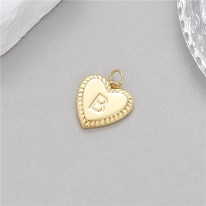 Détail macro du pendentif coeur doré avec lettre B gravée et bordure torsadée chic