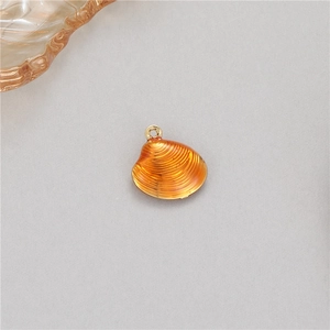 Macro detail of amber orange scallop shell pendant with 14k gold plated ring
