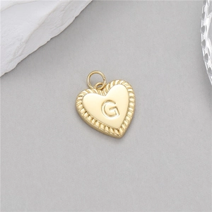 Vue détaillée d'un pendentif coeur doré avec lettre G et bordure texturée torsadée