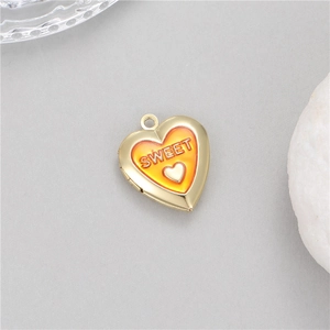 Macro detail of heart-shaped gold locket with orange enamel and SWEET engraving