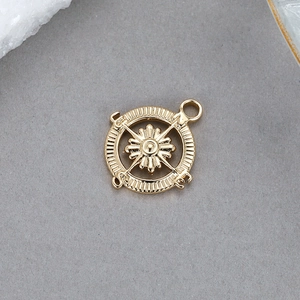 Macro shot of 14K gold plated compass charm featuring N S E W directional engravings