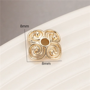Macro view of 8mm gold plated four-petal flower spacer bead with spiral texture