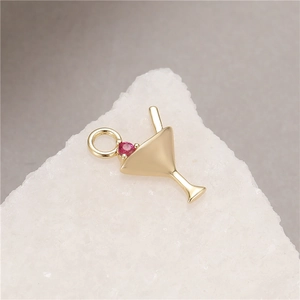 Macro shot of gold martini glass charm with a pink cubic zirconia and jump ring