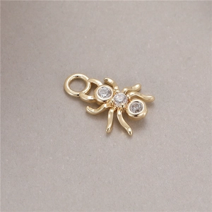 Detailed view of a golden spider pendant with micro-inset zircons and a small hook