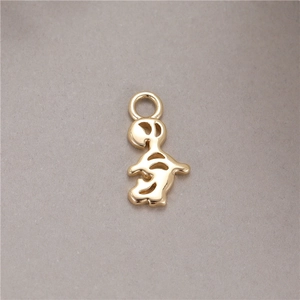 Gold-plated cartoon character pendant with hollow design and top ring on grey surface