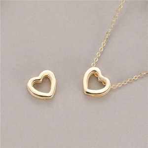 Elegant gold-tone hollow heart pendant with a fine chain necklace on a grey background