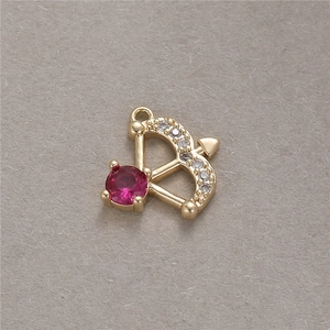 Makro-Detail eines 14K vergoldeten Amorpfeil-Anhängers mit rotem Zirkonia-Stein