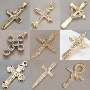 Collezione di nove ciondoli a croce dorati con cristalli di zircone e motivi vari