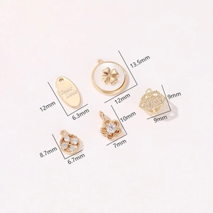 Dettagli di vari ciondoli a fiore placcati in oro e charms portafortuna con zirconi