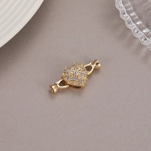 Detailed macro view of heart-shaped gold-plated jewelry clasp set with cubic zirconia stones