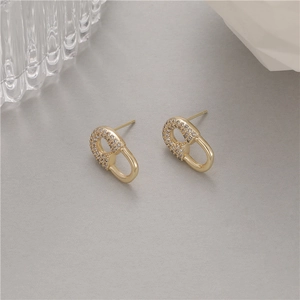 Golden paperclip heart earrings with micro-set zircons on neutral grey background