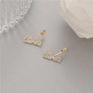 Golden Love letter stud earrings with sparkling pave zircon stones on a modern background