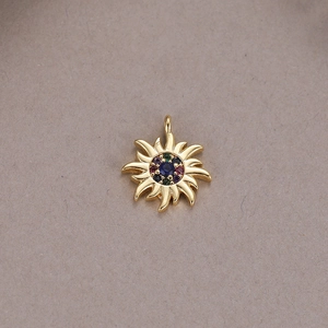 Detailed close-up of 14K gold sun pendant featuring a central blue gemstone and colored zircons
