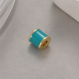 Primer plano macro de cuenta cilíndrica en esmalte turquesa y oro para joyería DIY