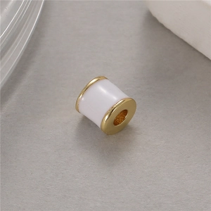 Vista macro de una cuenta cilíndrica blanca y dorada para pulseras y collares de bricolaje