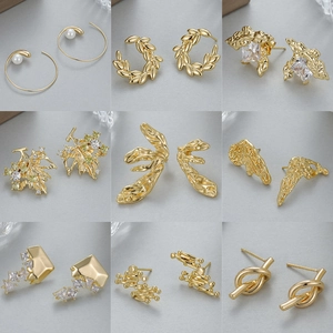 Set de 9 pendientes dorados con circonitas y perlas sobre superficie gris claro
