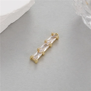 Détail macro du pendentif en zircon baguette 14K doré avec trois pierres précieuses