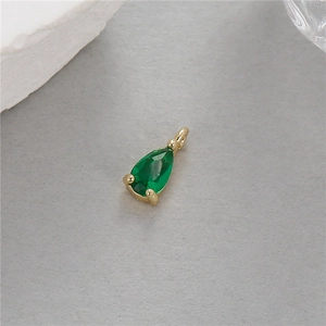 Gros plan d'un pendentif goutte plaqué or 14K avec une pierre de zircon vert