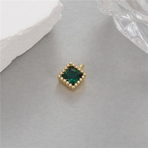 Détail d'un pendentif carré en or 14K avec zircon vert émeraude et bordure perlée