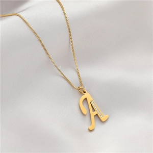 Macro shot of gold letter A pendant with zircon inlay on silky white fabric