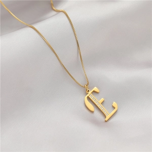 Close-up of golden letter E necklace pendant with sparkling zircons on satin fabric