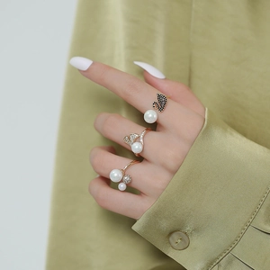 Detailed close-up of 14K gold plated adjustable rings with pearls and swan design