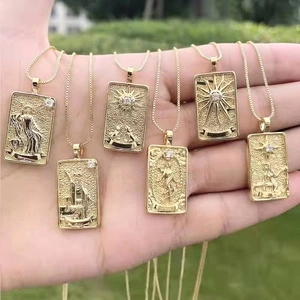 Makroansicht von 14K vergoldeten Tarot-Anhängern mit Himmelsmotiven in der Hand