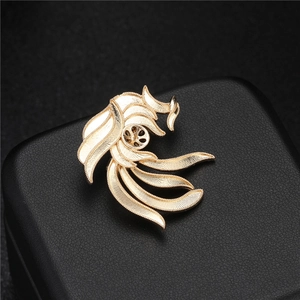Elegant gold phoenix feather brooch with pearl base displayed on premium black leather
