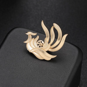 Elegant gold phoenix brooch with filigree details and pearls on black leather texture