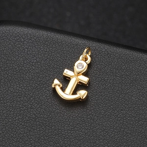 Polished 14K gold plated anchor pendant with sparkling zircon on black leather background