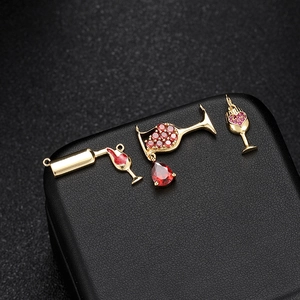Detailed view of 14k gold-plated wine glass charms with red enamel and crystals